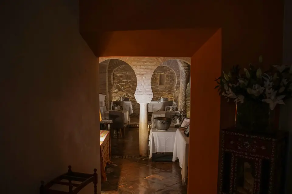 Sala restorana s lukovima od cigle i postavljenim stolovima.